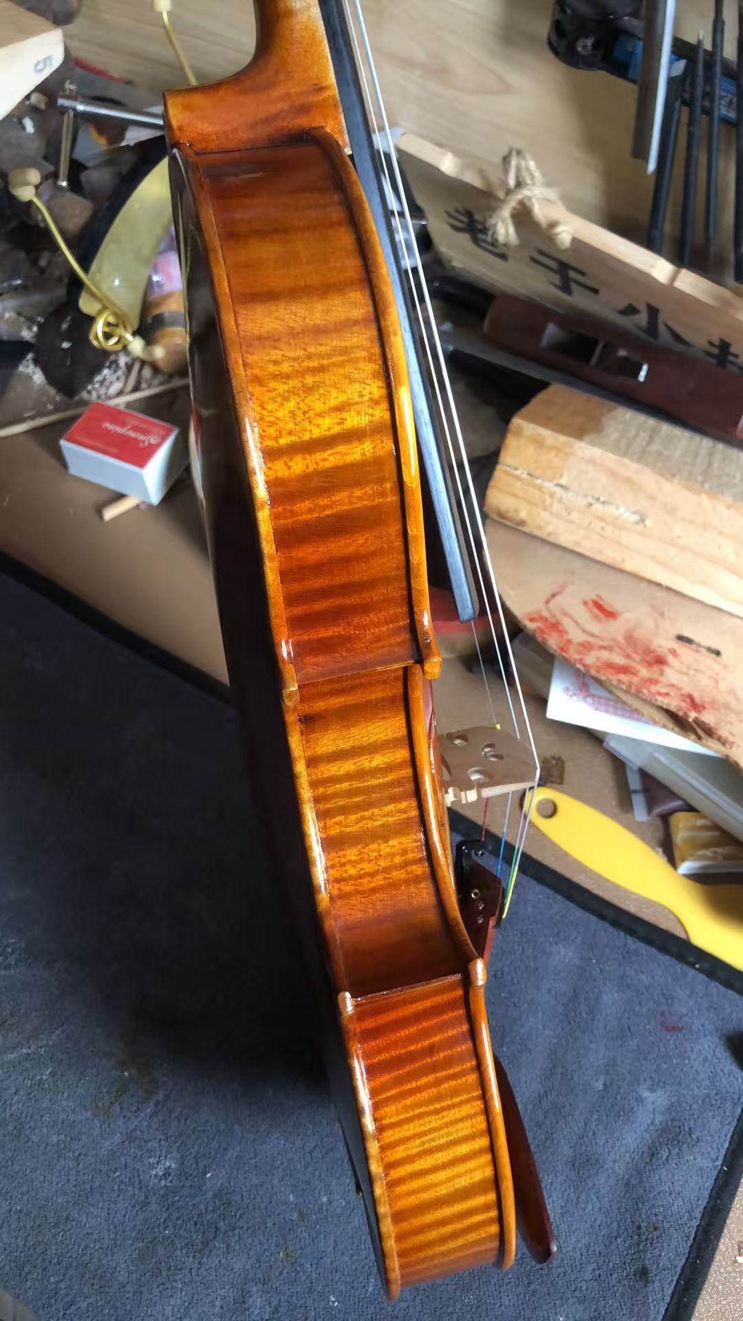 The flamed maple back of a violin, varnished by hand